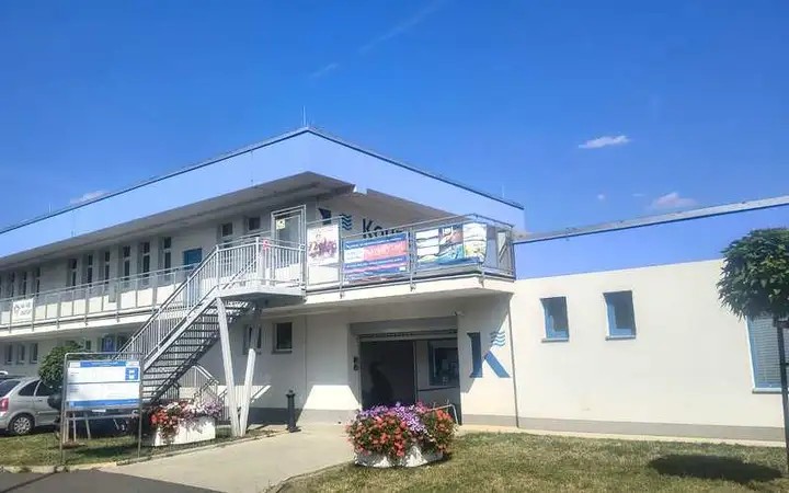 Budova a vstup do letního koupaliště v Kadani za slunečného dne